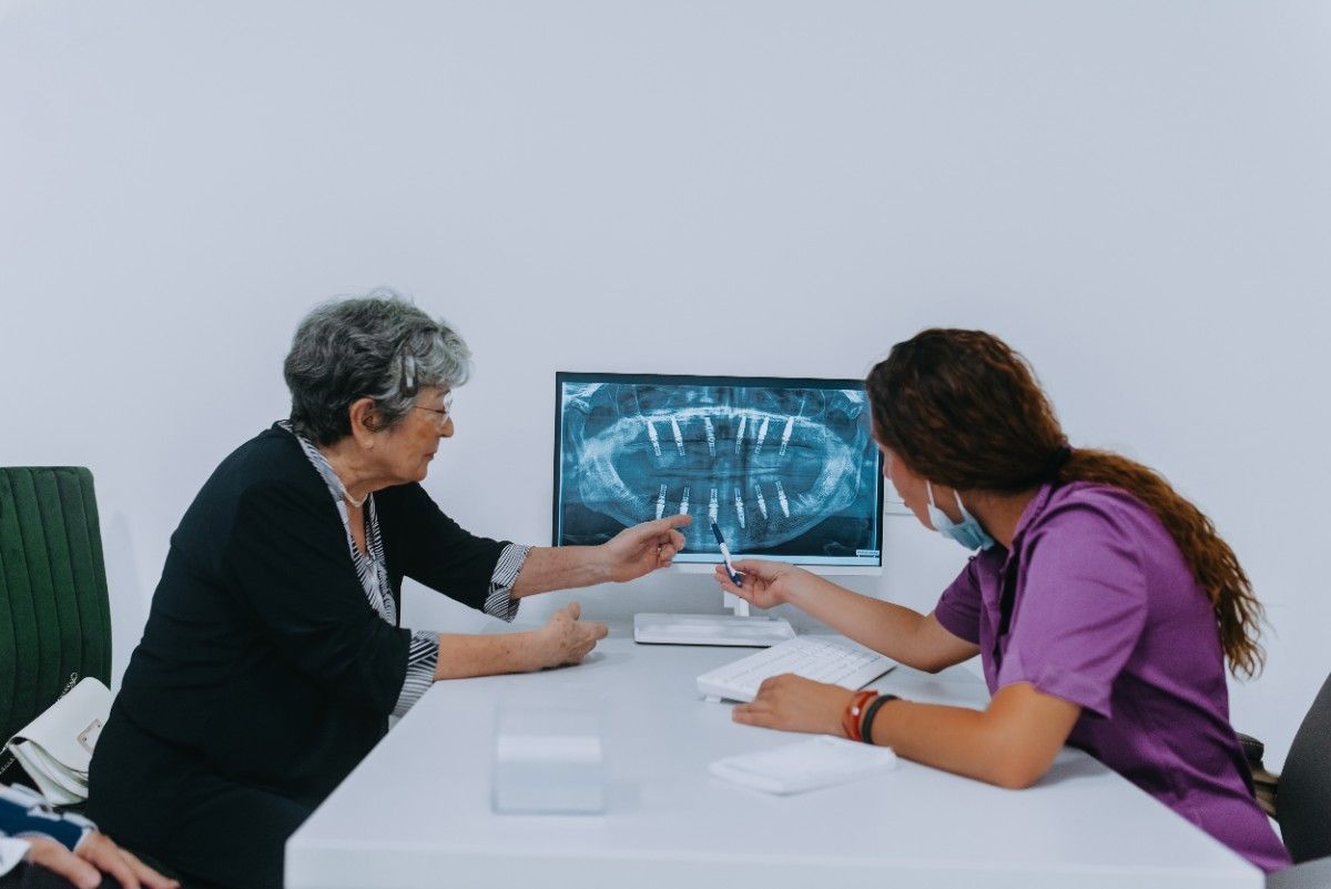 Patient discussing dental implant treatment plan with dentist during consultation.